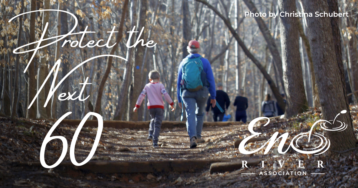 "Protect the Next 60". A child treks along a woody trail beside an adult hiker with grey hair. Photo by Christina Schubert.